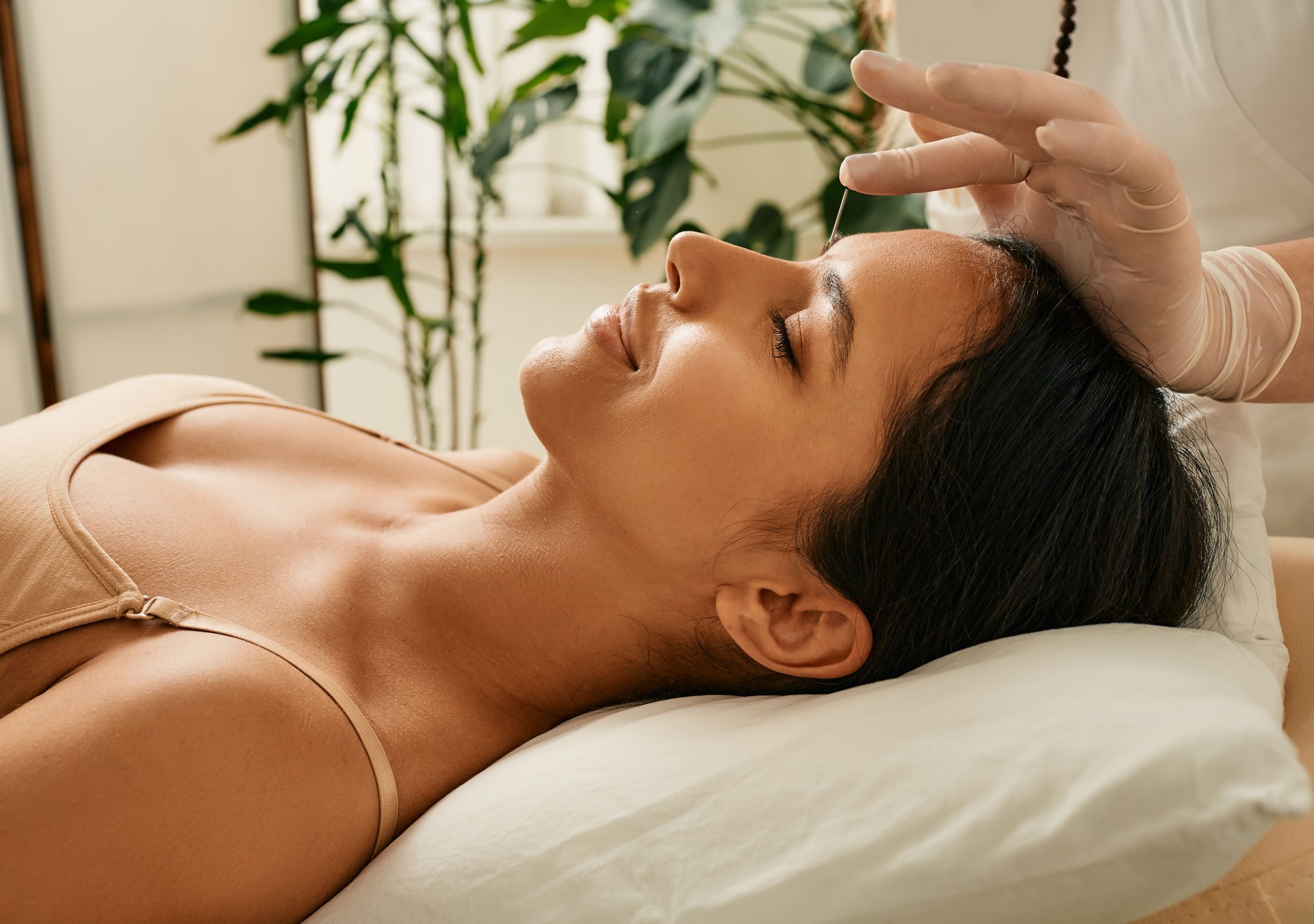 Reflexologist inserts acupuncture needles into acupuncture point on female head for headaches treatment. Traditional chinese medicine, reflexology
